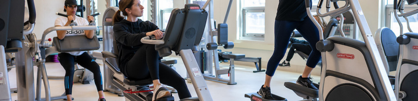 People exercising on various machines in a fitness center.
